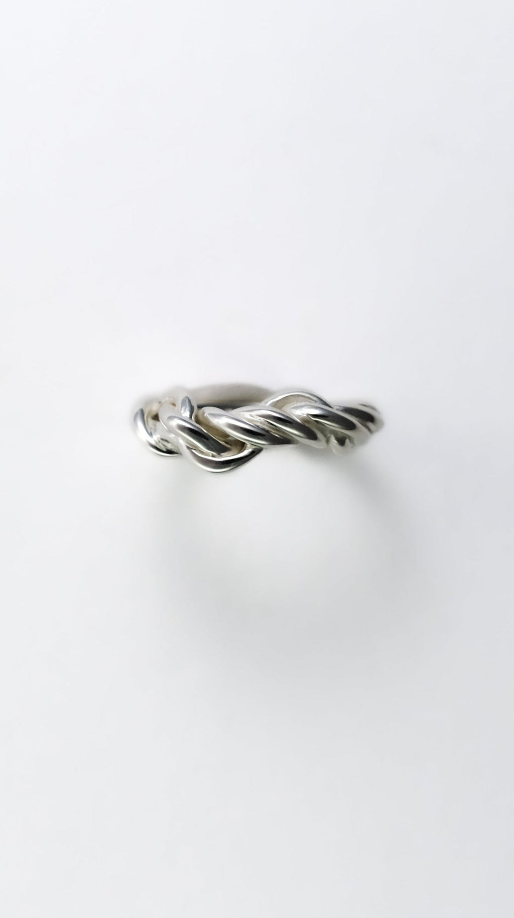Silver ring with a twisted design on a white background