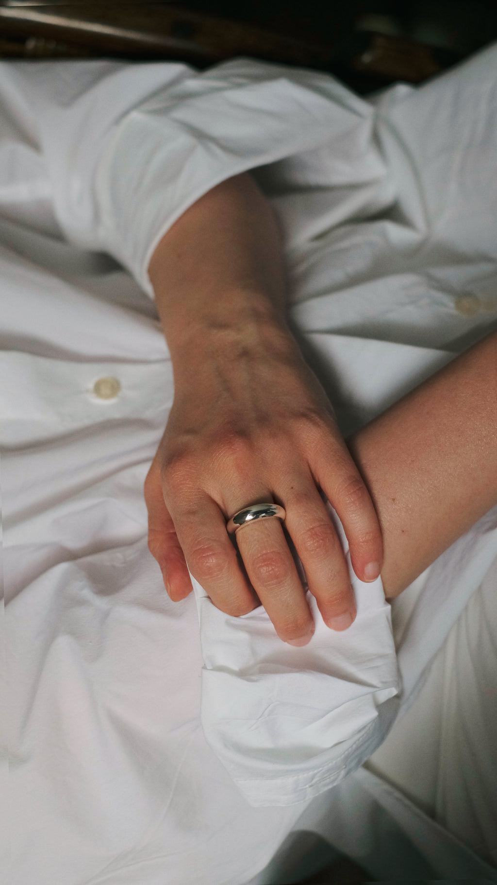 Close-up of a hand holding another hand with a ring, against a white background.