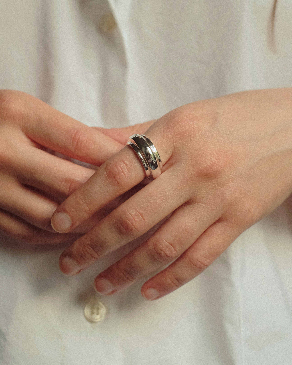 Close-up of hands with a ring on a light fabric background