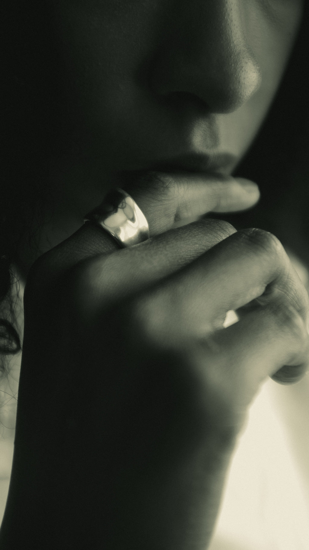 Close-up of a person with a silver ring holding their chin 