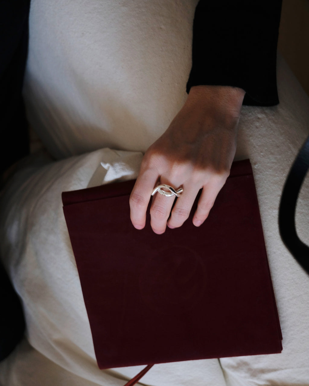 Hand with a ring holding a red packaging on a white surface