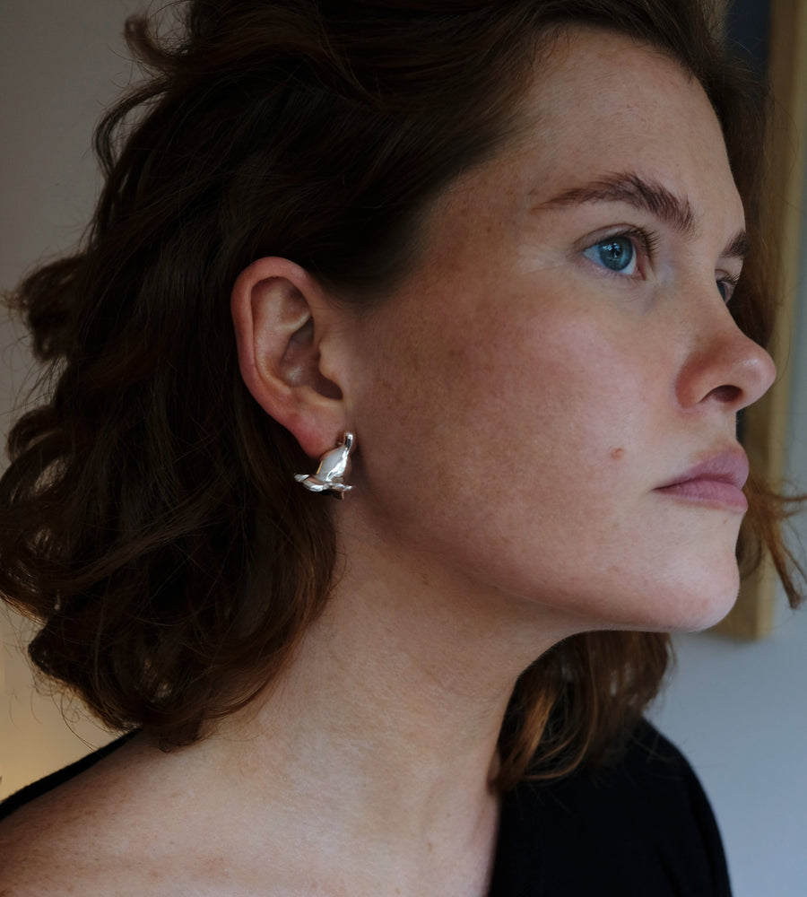 Close-up of a woman wearing a silver earring with a blurred background