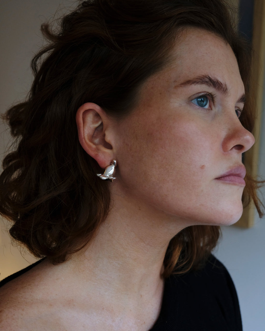 Close-up of a woman wearing a silver earring with a blurred background