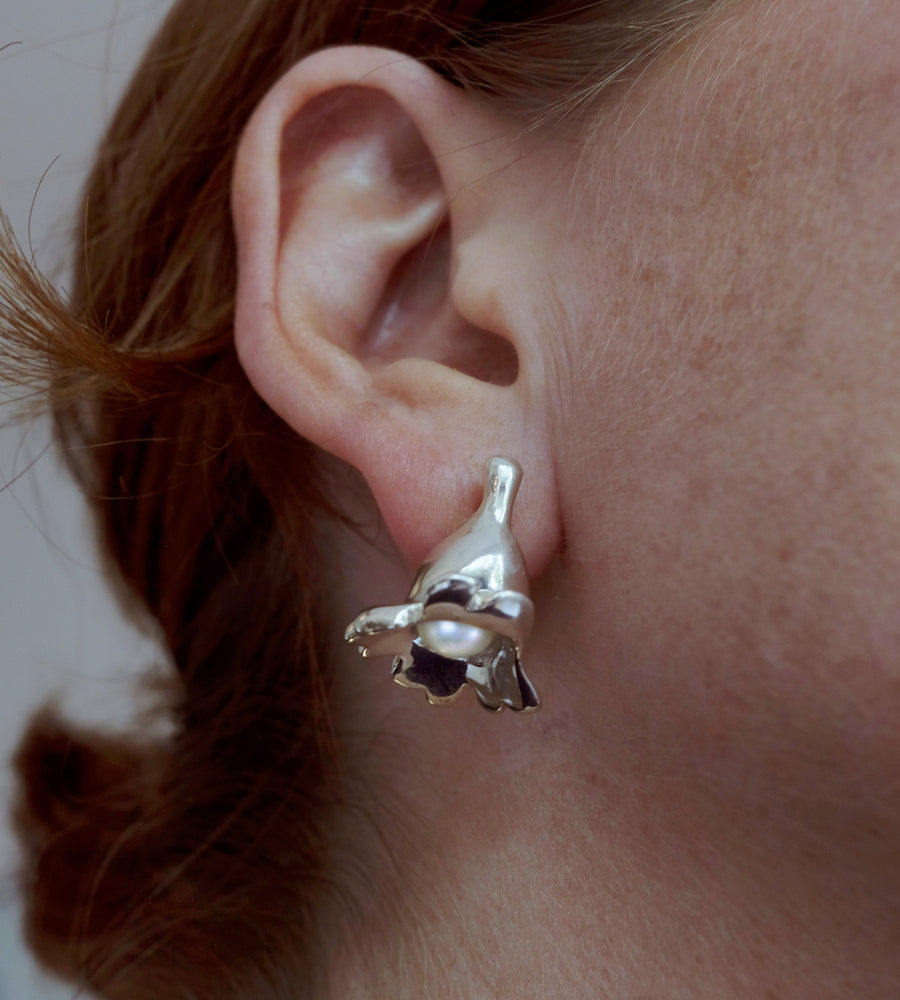 Close-up of a person wearing a silver earring with a pearl