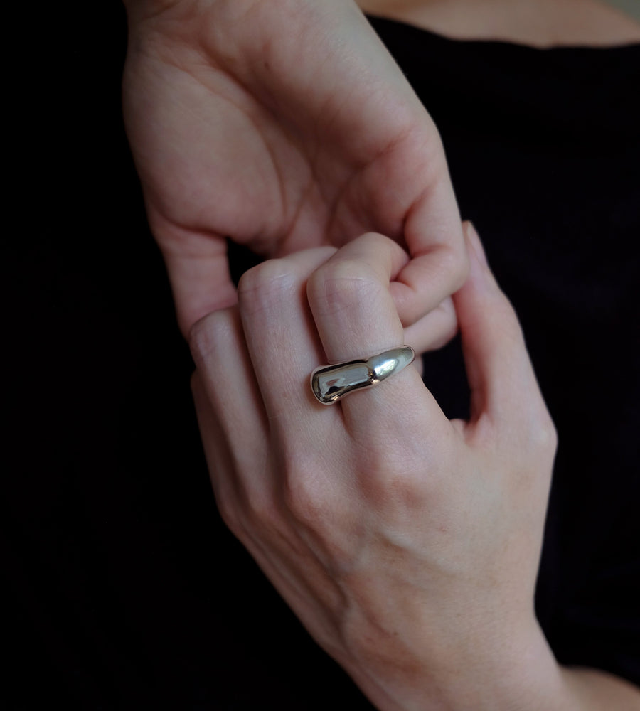 Close-up of a hand wearing a silver ring on a dark background