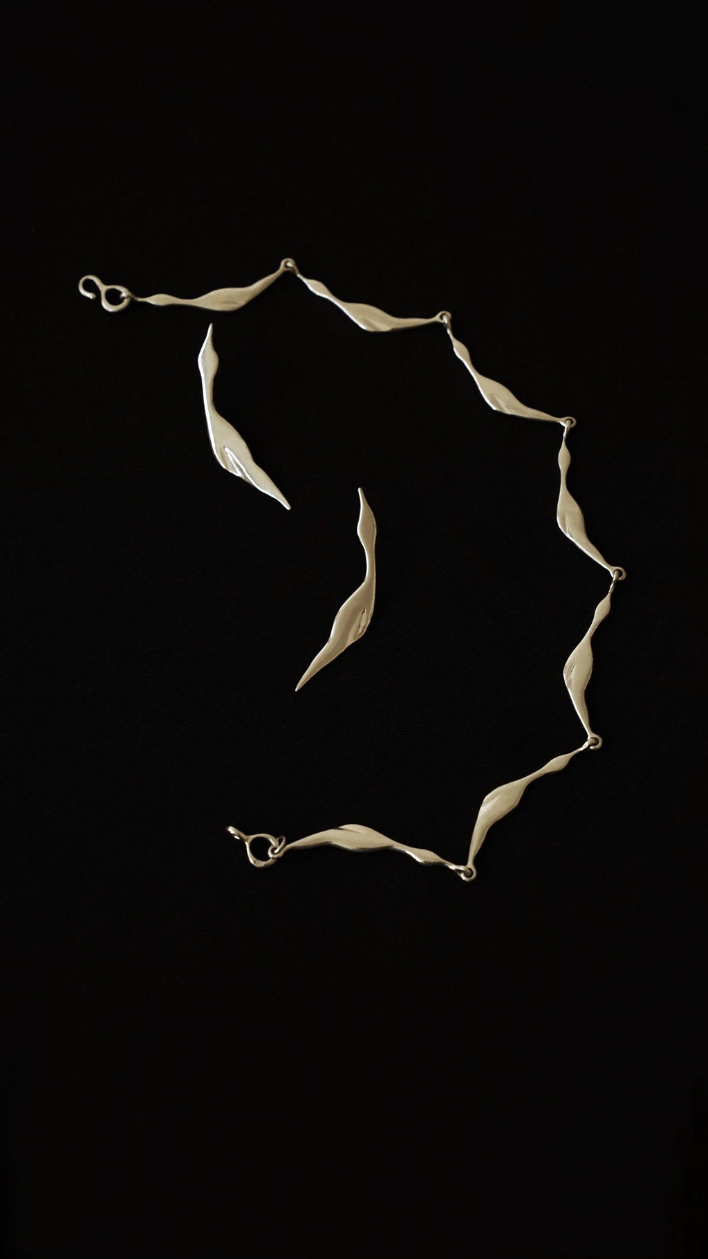 Silver necklace and earrings on a black background