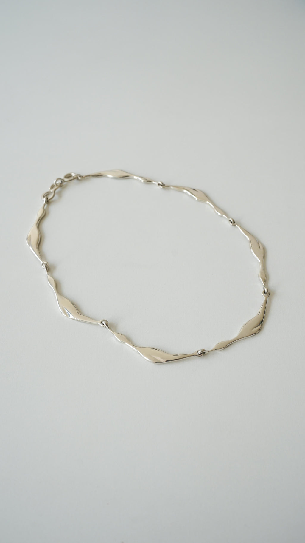 Silver necklace on a light gray background